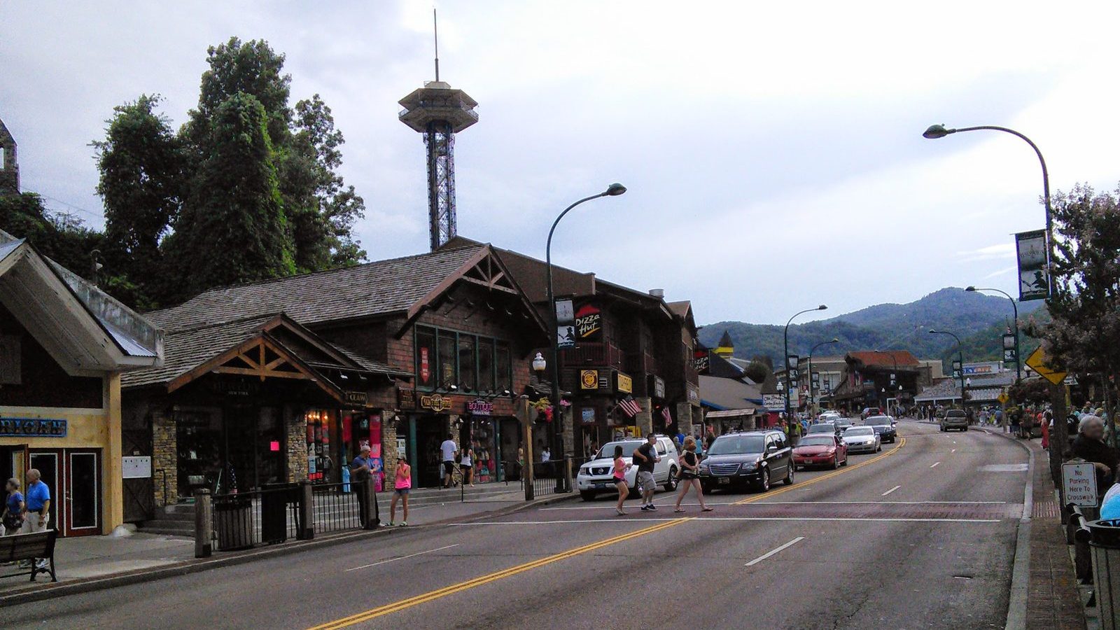 The Parkway in downtown Gatlinburg with shops on the left, the Space Needle behind them and the Smoky Mountains at the end of the street